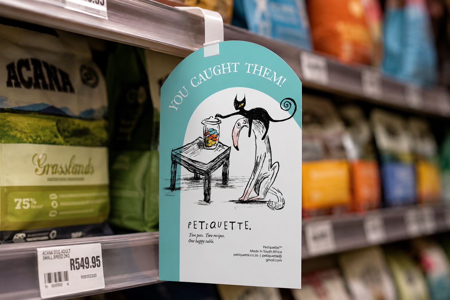 Petiquette shelf wobbler in a pet shop aisle — “You caught them!” with the cat stealing treats from the dog’s jar
